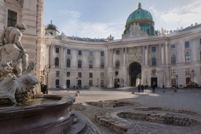 The green copper dome of the Hofburg's Michaelertor above Michaelerplatz, with the excavated Roman outlines set into the cobbles.