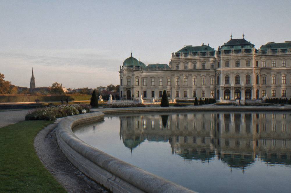 The Upper Belvedere's sandstone facade reflected in the long garden pond in calm morning light