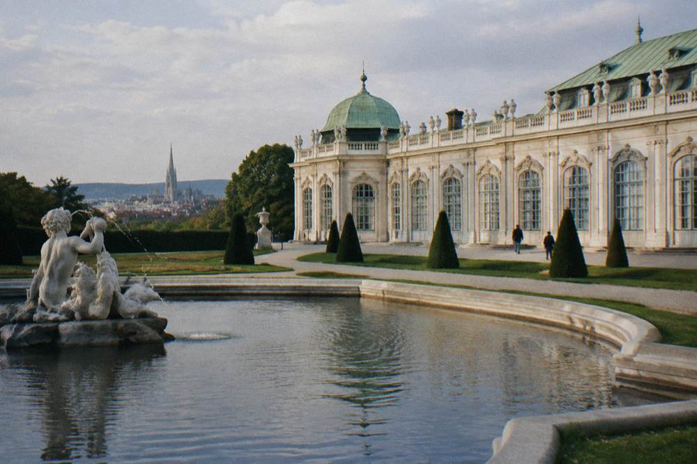 The Lower Belvedere's orangery side with a fountain basin in the foreground and clipped lawns around it