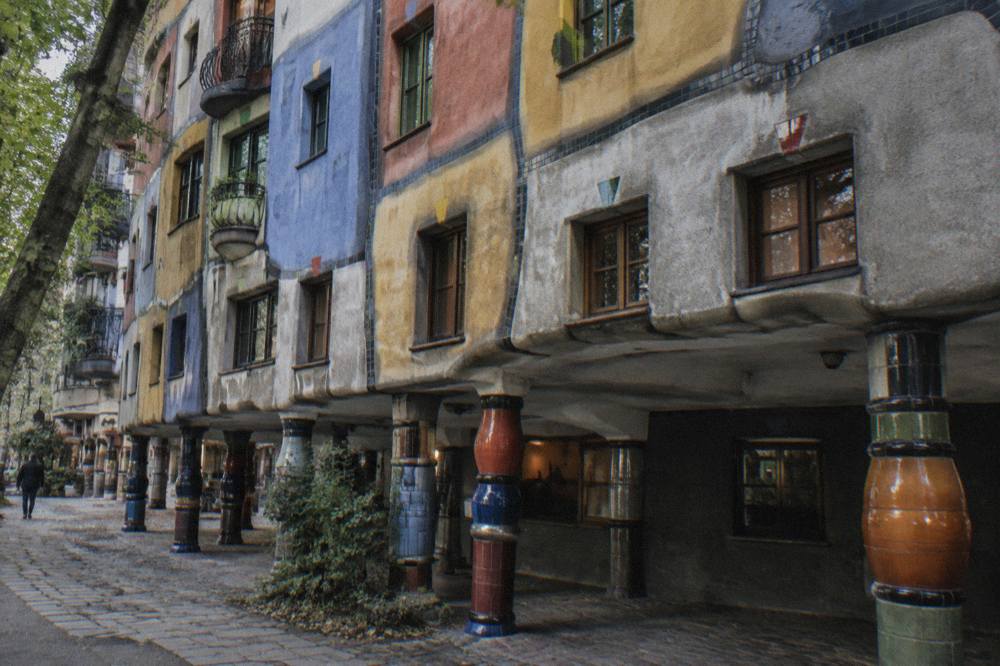 The uneven coloured bands and ceramic columns of the Hundertwasserhaus ground floor seen from the pavement