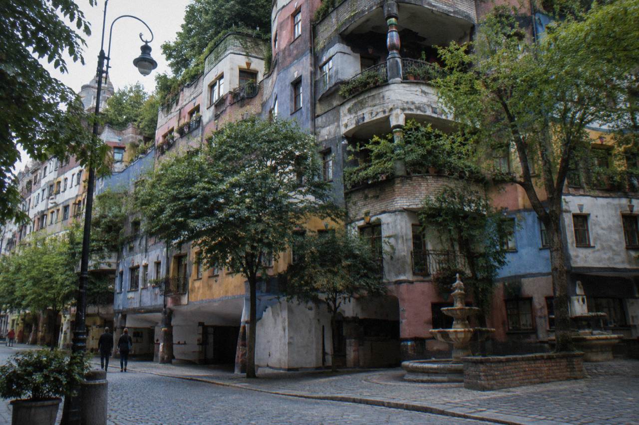 The Hundertwasserhaus apartment block with its wavy coloured facade and tree-planted balconies seen from the street corner