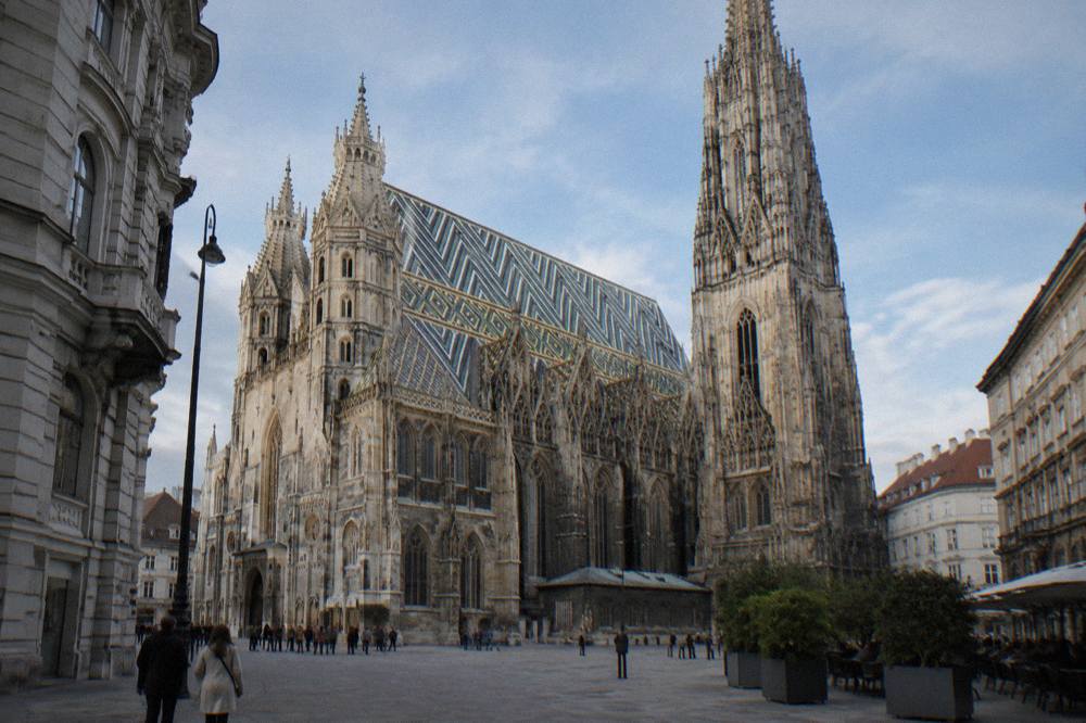 The tiled roof pattern and stone buttresses of the cathedral seen from the paving of Stephansplatz