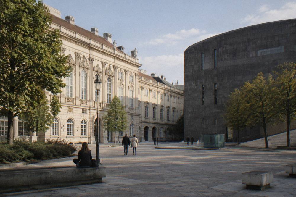 The pale Baroque stables wing meeting the dark basalt museum block across the MuseumsQuartier courtyard in morning light