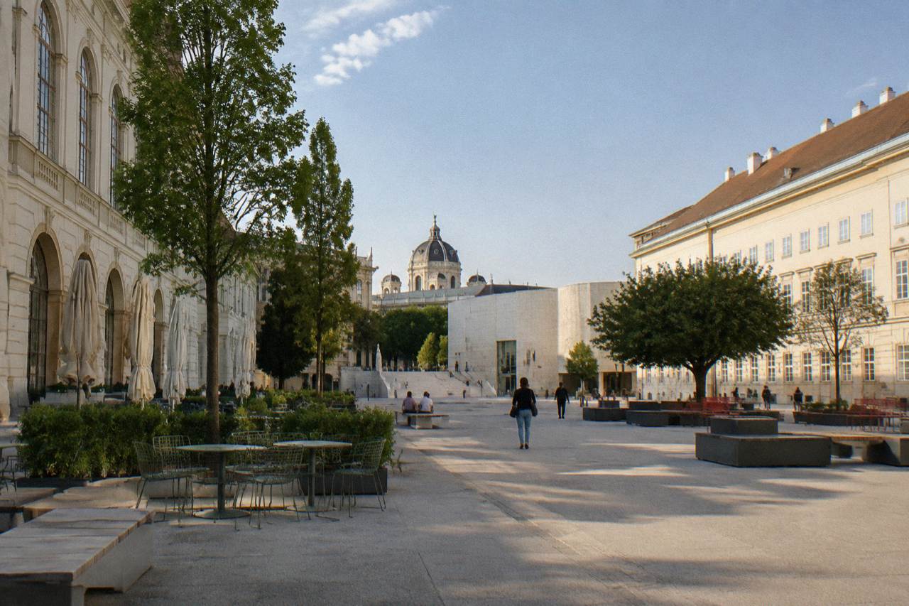 The wide MuseumsQuartier courtyard framed by museum facades with open seating furniture and a clear sky