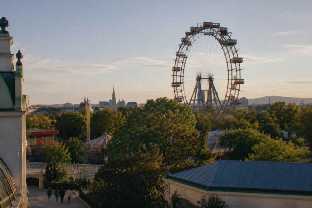 The Riesenrad Ferris wheel rising above the Prater treetops and fairground roofs in side light