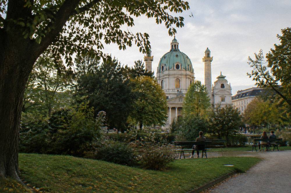 The Karlskirche dome and columns seen across the Resselpark trees