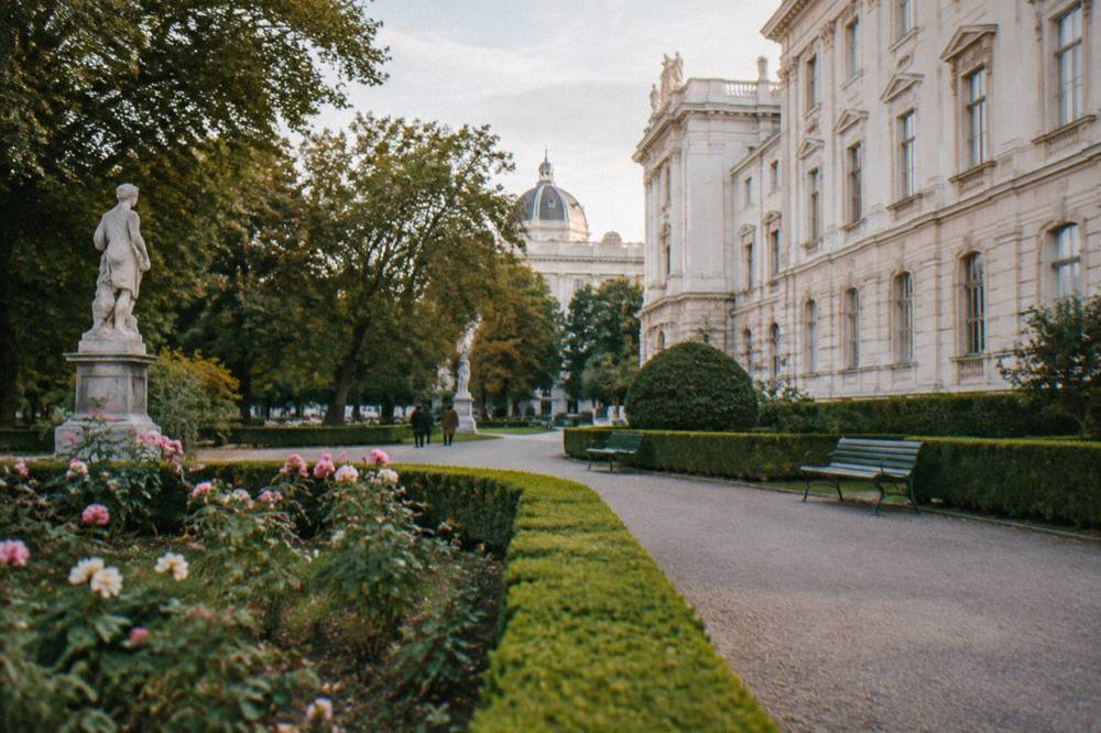 Formal paths and trimmed hedges in the Burggarten beside the pale Hofburg wing