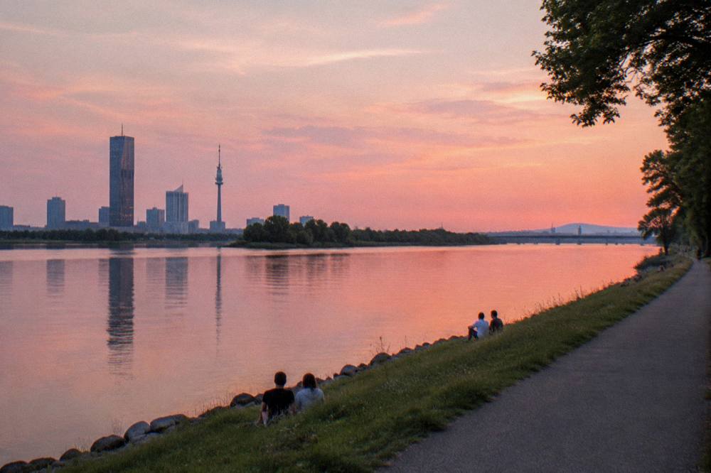 Evening light over the wide Danube channel with the thin silhouette of the Donauinsel and still water reflecting a pink sky