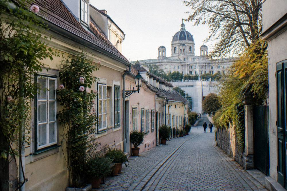 A cobbled Spittelberg lane with low pastel Biedermeier houses leading toward the MuseumsQuartier in soft morning light