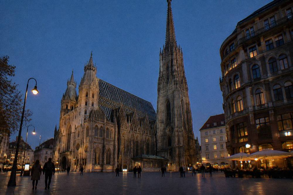 The cathedral's south tower rising into a dark blue sky above Stephansplatz paving after sunset