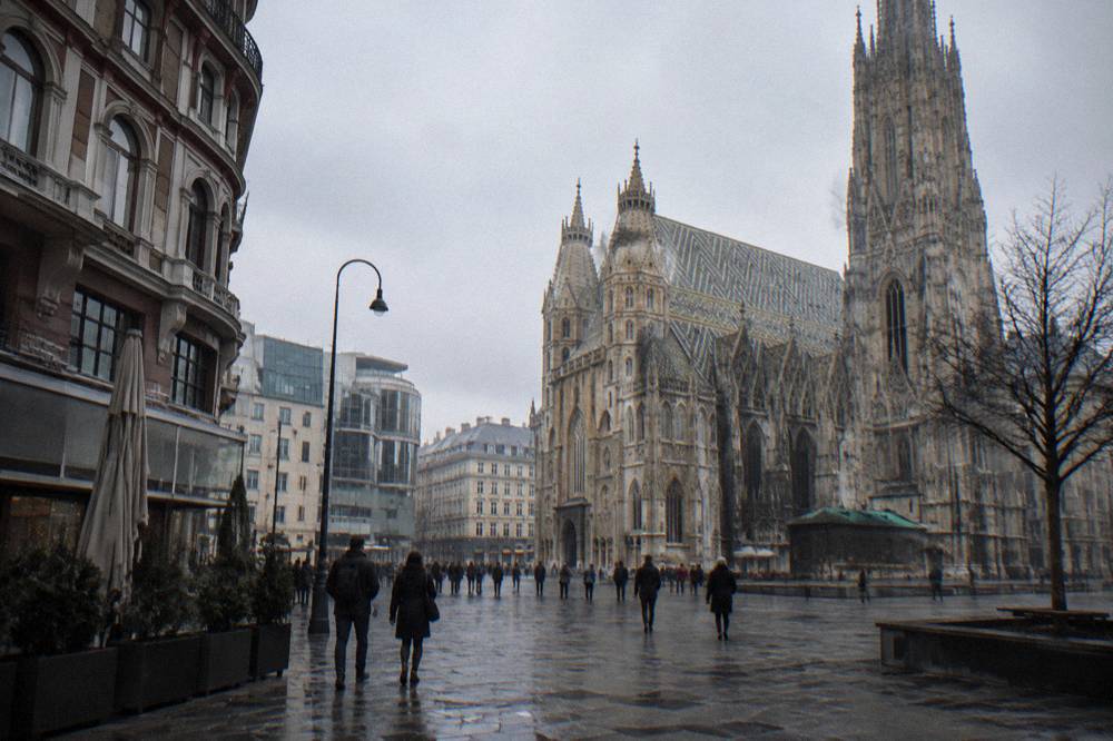 Stephansplatz in winter with bare winter air, wet cobbles and distant pedestrians in dark coats under a pale grey sky