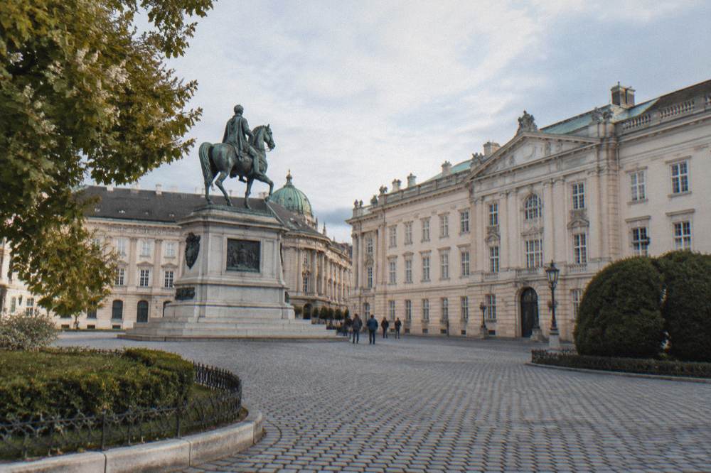 The cobbled Josefsplatz with its equestrian monument and the pale library wing, a small group of visitors tiny in the middle distance