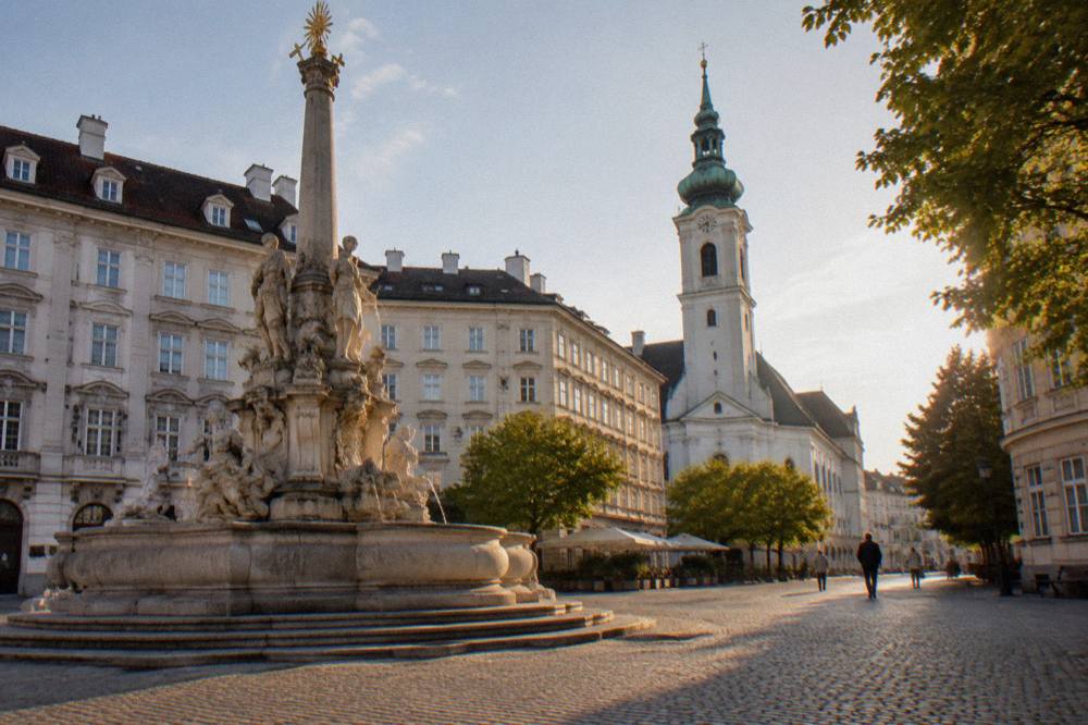 Neuer Markt square with its Baroque fountain and a church tower behind, cobbles in warm morning light