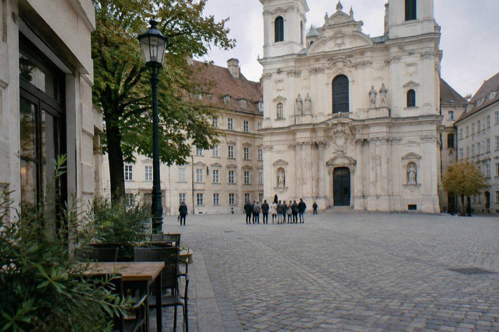 Am Hof square with the pale Baroque church facade and a small group gathered far across the open cobbles