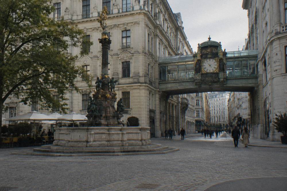 Hoher Markt square with its ornate marriage fountain and the glass-covered clock bridge above the street, seen from the corner
