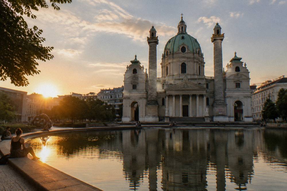 Karlsplatz on a summer evening with the Karlskirche dome beyond the reflecting pond and a golden low sun