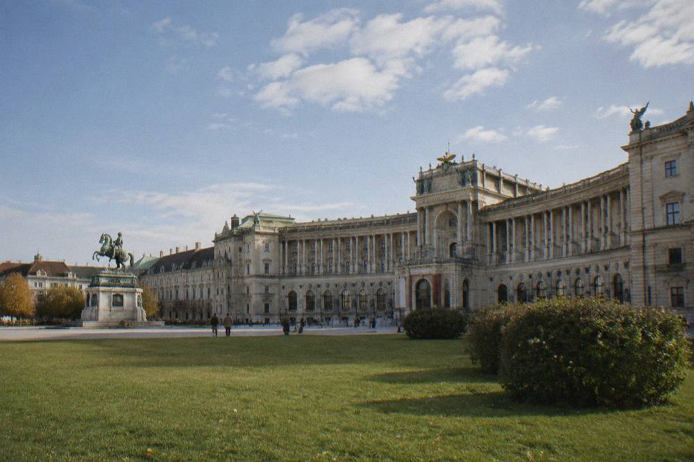 Heldenplatz with its open meadow and the curved Hofburg wing, equestrian statue small to one side, under a wide sky