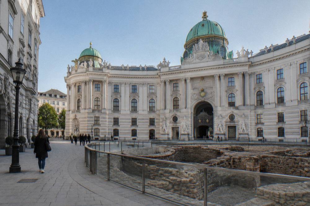 The Hofburg Michaelertor dome and ancient Roman excavation ring on Michaelerplatz under clear morning sky