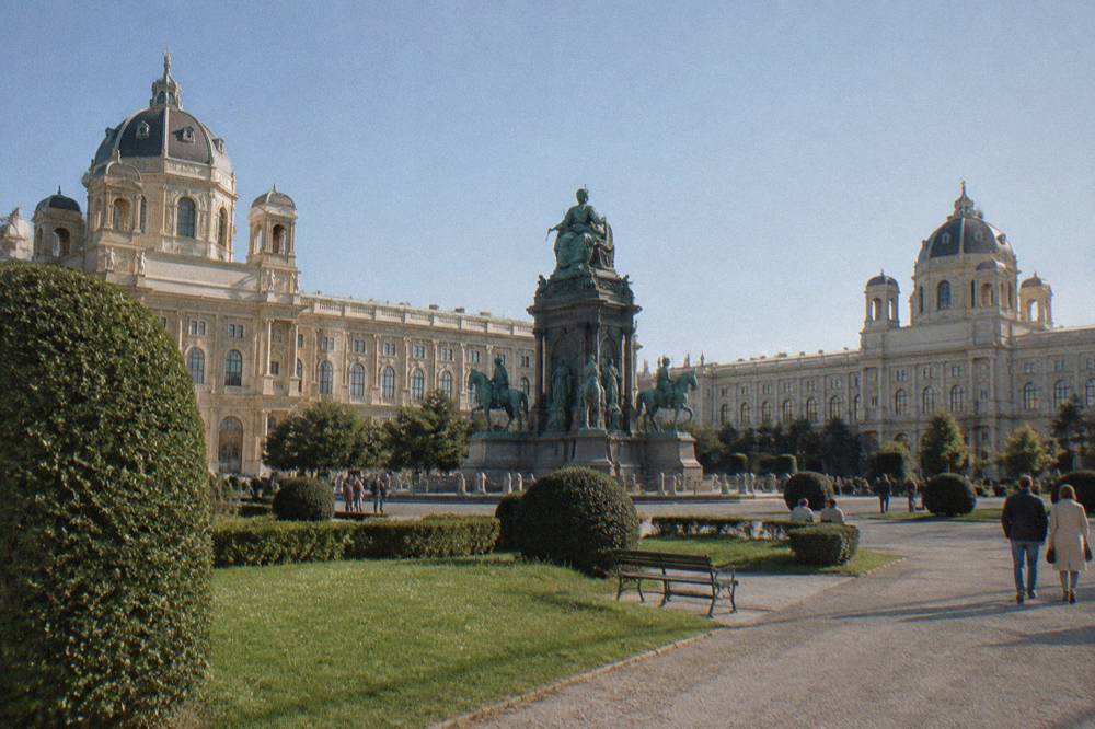 Maria-Theresien-Platz gardens with the large monument and the twin museum domes under a clear sky