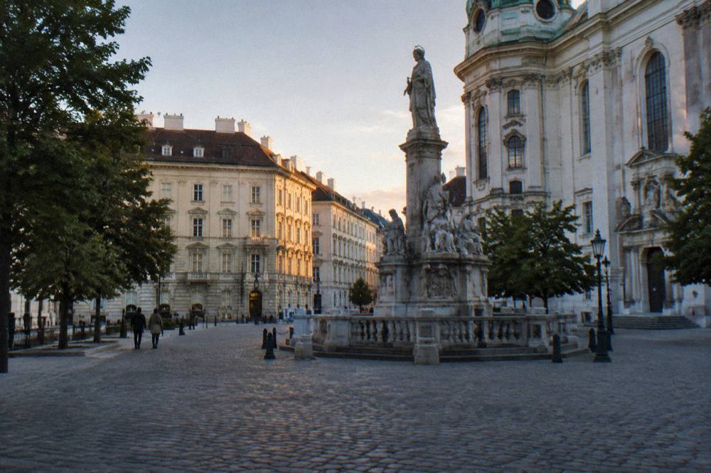 The cobbled Josefsplatz in soft evening light with the monument and a small fountain-less foreground